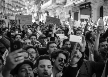 Protesters gather in a darkened street, holding phones and chanting amid Iran's internet blackout.