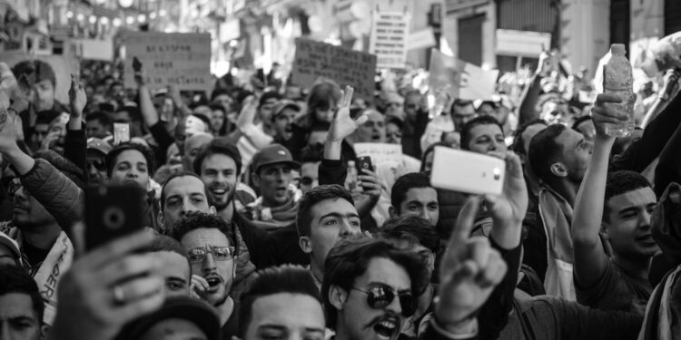 Protesters gather in a darkened street, holding phones and chanting amid Iran's internet blackout.