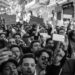 Protesters gather in a darkened street, holding phones and chanting amid Iran's internet blackout.
