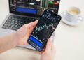 Trader analyzing crypto charts on a smartphone with a Telegram app interface displayed.