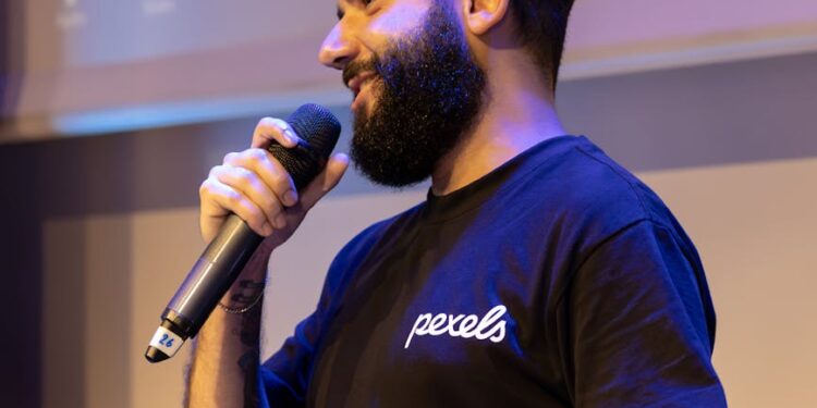 Joe Lubin speaking at a crypto conference, with visuals of DeFi logos in the background.