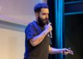 Dan Finlay speaking at a crypto conference, gesturing passionately to the audience.