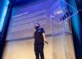Elon Musk speaking at a podium with AI-related graphics in the background.