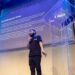 Elon Musk speaking at a podium with AI-related graphics in the background.