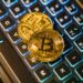 Golden Bitcoin coins stacked on a computer keyboard, symbolizing crypto finance and security.