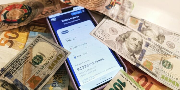 A smartphone displaying the Pix payment app alongside cash and international currency symbols.