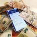 A smartphone displaying the Pix payment app alongside cash and international currency symbols.