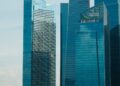 HSBC and Standard Chartered logos with a digital currency symbol and Hong Kong skyline.