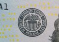 Jerome Powell speaking at a podium with Federal Reserve emblem, addressing financial regulations.