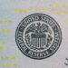Jerome Powell speaking at a podium with Federal Reserve emblem, addressing financial regulations.
