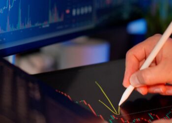 A financial analyst examining Bitcoin trends with declining charts in the background.