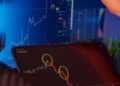 A business professional reviews financial graphs on a laptop, featuring crypto and fiat integrations.