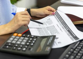 Nishad Singh seated at a desk, reviewing financial documents related to cryptocurrency regulations.