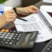 Nishad Singh seated at a desk, reviewing financial documents related to cryptocurrency regulations.