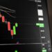 A dark screen with stock charts and a warning sign, representing a trading suspension.