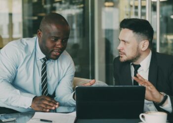Two business professionals discussing stablecoin technology at a modern office.