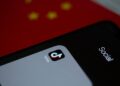 Graphic showing a smartphone with the Bitchat app logo and a backdrop of China's flag.