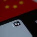 Graphic showing a smartphone with the Bitchat app logo and a backdrop of China's flag.