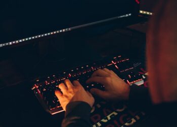 A hacker's hand typing on a keyboard with crypto charts on the screen, symbolizing a cyber attack.