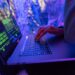 A hacker typing on a laptop with cryptocurrency logos in the background, highlighting DeFi vulnerabilities.