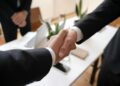 Business executives shaking hands over a financial deal, symbolizing a major acquisition.