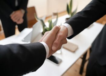 Business executives shaking hands over a financial deal, symbolizing a major acquisition.