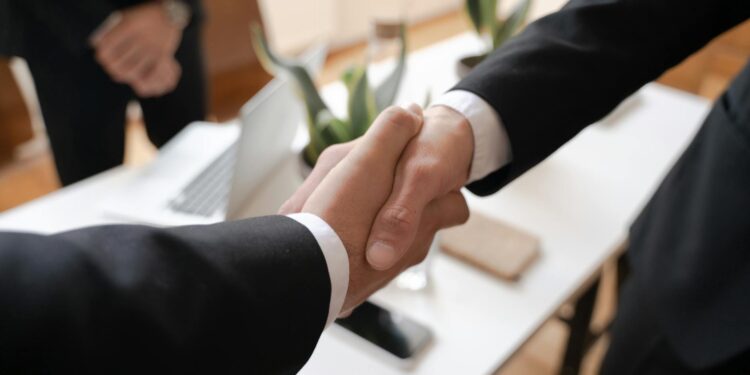Business executives shaking hands over a financial deal, symbolizing a major acquisition.
