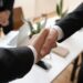 Business executives shaking hands over a financial deal, symbolizing a major acquisition.