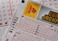 A gavel rests on a legal document surrounded by lottery tickets and gambling tokens.
