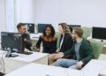 Diverse group of apprentices engage with computers in a modern training facility.