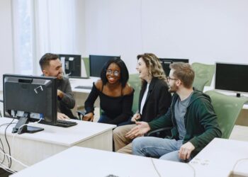 Diverse group of apprentices engage with computers in a modern training facility.