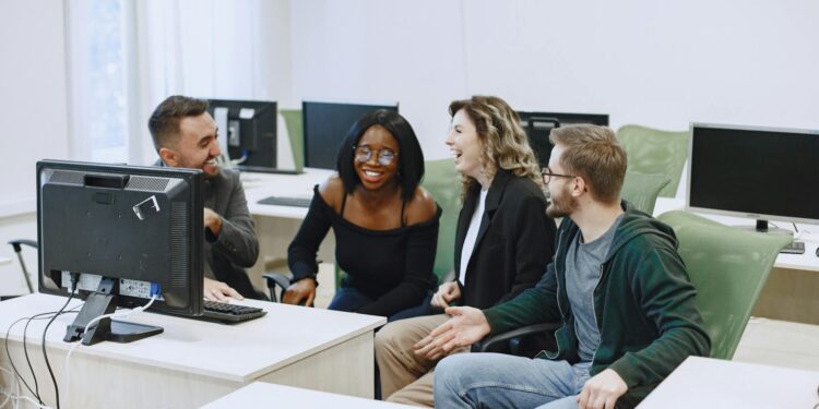 Diverse group of apprentices engage with computers in a modern training facility.