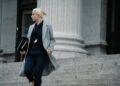 A woman standing in front of a courthouse, linked to a Bitcoin fraud case.