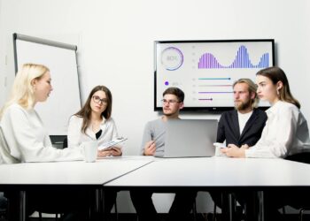 A corporate team celebrating in front of a digital display showing record valuations.