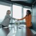 Payward CEO shaking hands with Bitnomial executives in a modern office setting.