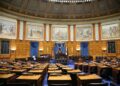 Legislators discussing AI therapy chatbot regulations in a statehouse setting.