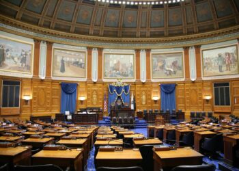 Legislators discussing AI therapy chatbot regulations in a statehouse setting.