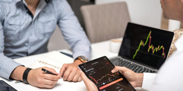 Two financial professionals discuss crypto technology with JPM Coin graphics on a screen.