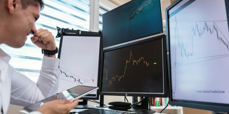 A trader monitors Bitcoin prices and oil market charts on multiple screens.
