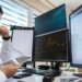 A trader monitors Bitcoin prices and oil market charts on multiple screens.