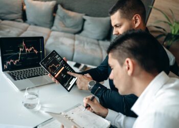 Two professionals discussing blockchain technology with digital graphs and charts in the background.