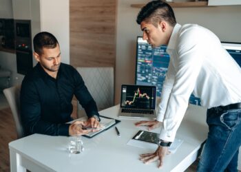 A group of professionals analyzing cryptocurrency data on screens in a corporate setting.