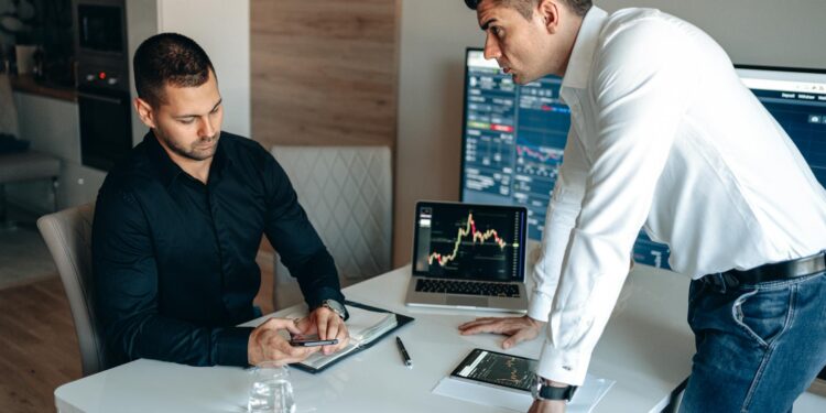 A group of professionals analyzing cryptocurrency data on screens in a corporate setting.