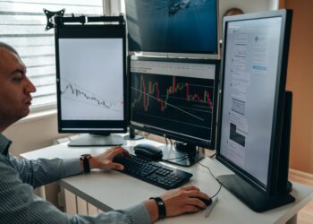 A trader analyzing cryptocurrency charts on multiple screens in a modern office environment.