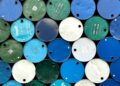 Oil barrels and Bitcoin coins juxtaposed with a US Navy ship in the background.