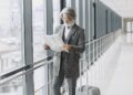 A man in a suit carrying a briefcase walks through an airport terminal.
