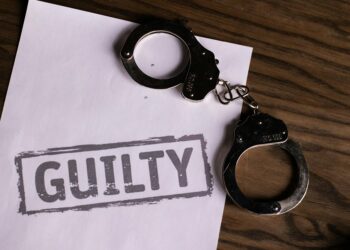 Delio CEO in handcuffs, leaving court after crypto fraud proceedings.