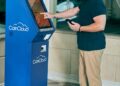 A crypto ATM in a public space with a warning sign about fraud risks.