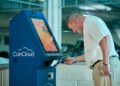 A cryptocurrency ATM in a public space surrounded by warning signs about fraud.