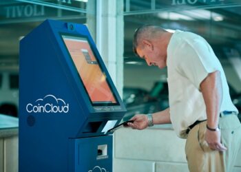 A cryptocurrency ATM in a public space surrounded by warning signs about fraud.